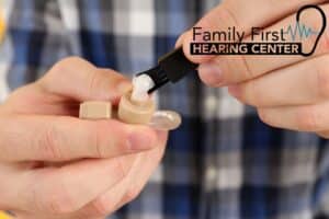 hands cleaning a hearing aid